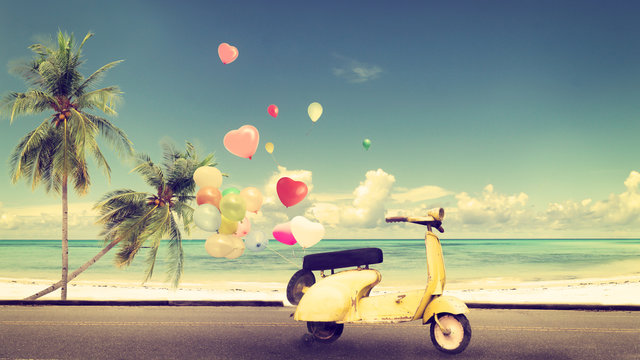 Classic yellow motorcycle with heart balloon on beach blue sky concept of love in summer and wedding honeymoon - vintage color effect