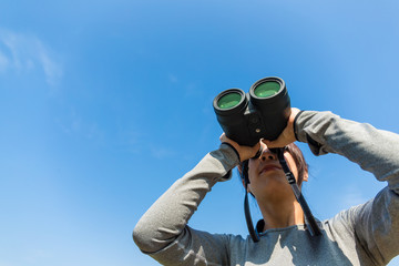 Woman use the binoculars with clear blue sky