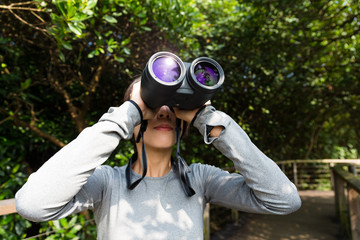 Woman looking though binoculars at jungle