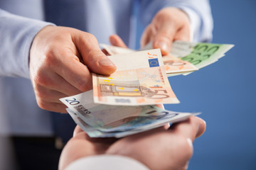 Businessman's  hands exchanging euro on blue background - obrazy, fototapety, plakaty