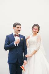 bride and groom attached to  face paper mustache , glasses