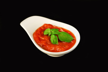 Tomato sauce with basil isolated on black background