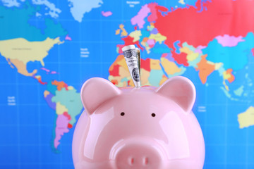 Money box pig on world map background