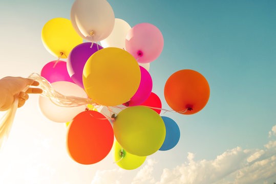 Woman hand holding colorful balloons in morning time. concept of happy birthday party. vintage filter effect