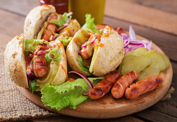 Hot dog - sandwich with pickles, red onions and lettuce on wooden background. Top view