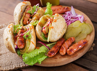 Hot dog - sandwich with pickles, red onions and lettuce on wooden background. Top view