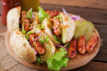 Hot dog - sandwich with pickles, red onions and lettuce on wooden background. Top view