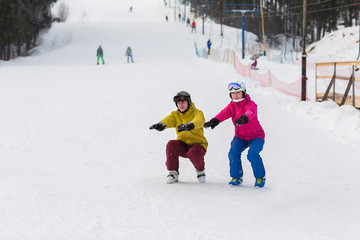 Young couple snowboarders slide down the slope in a winter day. Happy couple athletes.