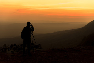 Silhouette of traveler when he is taking photograph on mountain