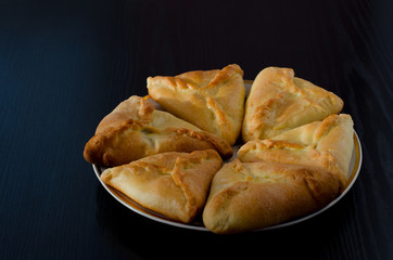 Plate with fresh fragrant pies on a black wooden table, lunch, echpochmak