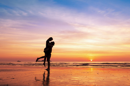 Couple kissing on the beach with beautiful sunset in background