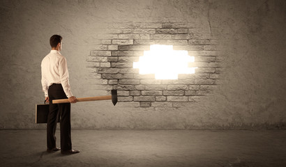 Business man hitting brick wall with hammer and opening a hole