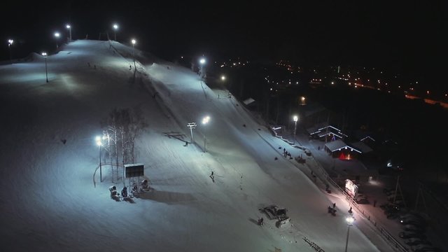 Aerial view night skiing and snowboarding at a ski resort 