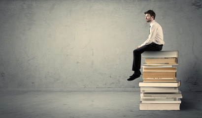 Student sitting on stack of books