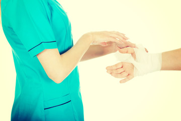 Woman doctor bandaging female hand.