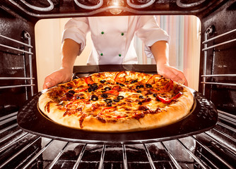 Chef cooking pizza in the oven.