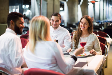 Obraz premium Two happy couples sitting at outdoor restaurant