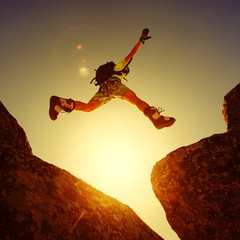 man jumping cliff with blue sky