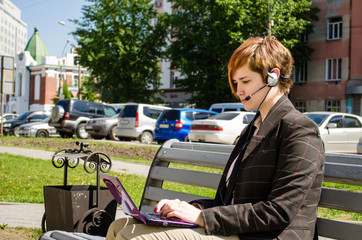 Young business woman with a laptop working outdoor sitting on th