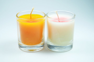white and orange candles aroma in clear glass on white background