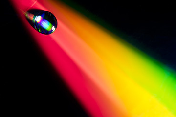 Water drop on dvd disk. Multi colored background, like a rainbow