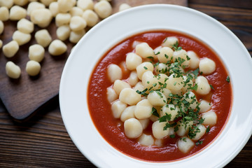 Italian gnocchi served with tomato sauce and parsley, closeup