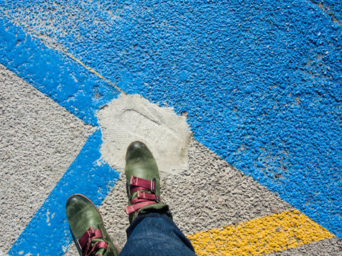 Aufsicht auf die grünen Stiefel einer stehenden Person auf Straße