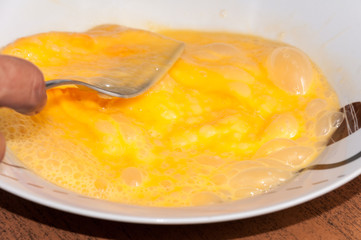 Whipping eggs in a plate for scrambled eggs