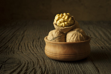 Walnut kernels and whole walnuts on rustic old wooden table