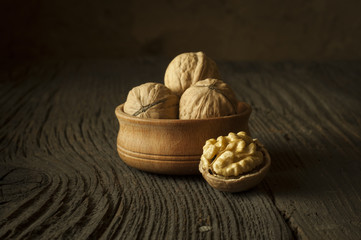 Walnut kernels and whole walnuts on rustic old wooden table