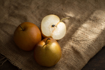 three pear apples lighted with ray of sun on canvas texture