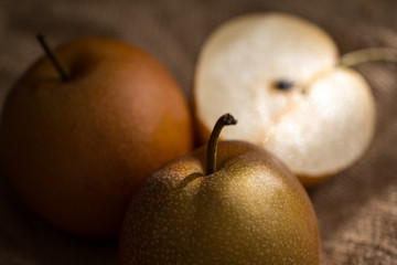 three pear apples lighted with ray of sun on canvas texture