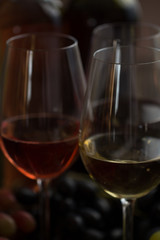 Three wineglasses of red, rose and white wine with three kinds of grapes on brown wood textured table