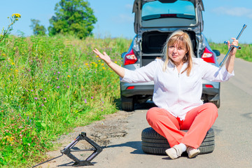 Fototapeta na wymiar angry female driver sitting at the wheel near the broken car