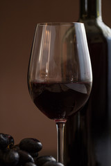 wineglass with red wine,bottle and grapes on brown background