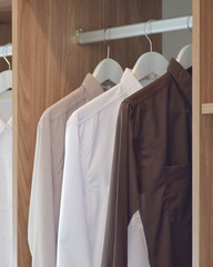 Classic color shirts hanging in wooden wardrobe