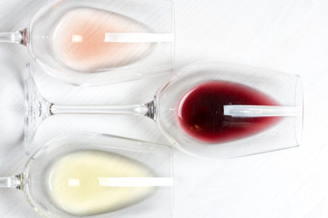three glasses of white, rose and red whine on white wood textured background 