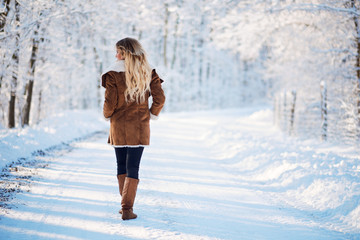 Young blonde woman walking winter park
