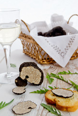 Cut black truffle with arugula and bread on old table