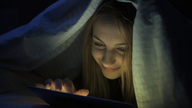 Girl  on the bed with tablet.