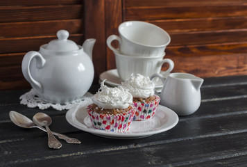 Delicious cupcakes and a tea set on a wooden table. Tea time. Vintage and rustic style