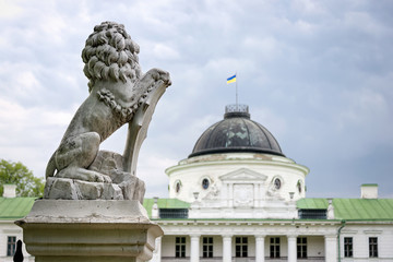 Obraz premium Statue of lion holding a shield in its paws. Regal lion leaning on empty heraldic shield near the castle entrance. The palace and park complex Manor Tarnowski, s.Kachanovka, Ukraine.