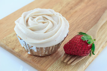 Vanilla cupcake with strawberry frosting and fresh strawberry
