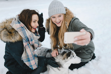 Two adorable girls posing with their husky dog on winter vacation day in park