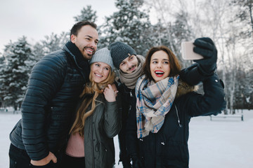 Cute young hipster couples posing in winter park on a bright day hugging each other and smiling
