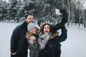 Fototapeta premium Cute young hipster couples posing in winter park on a bright day hugging each other and smiling 