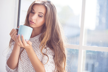 Beautiful lady sitting by the window indoor