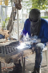 Worker welding steel in construction site.
