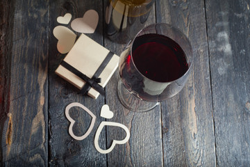 glass of red wine and a gift on a wooden background
