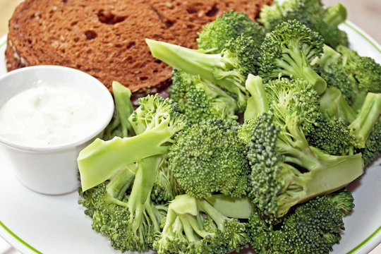 Nutritious Rye bread sandwich with a side of fresh Broccoli and a dipping sauce

